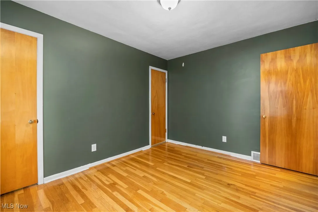 Unfurnished bedroom with wood finished floors and baseboards