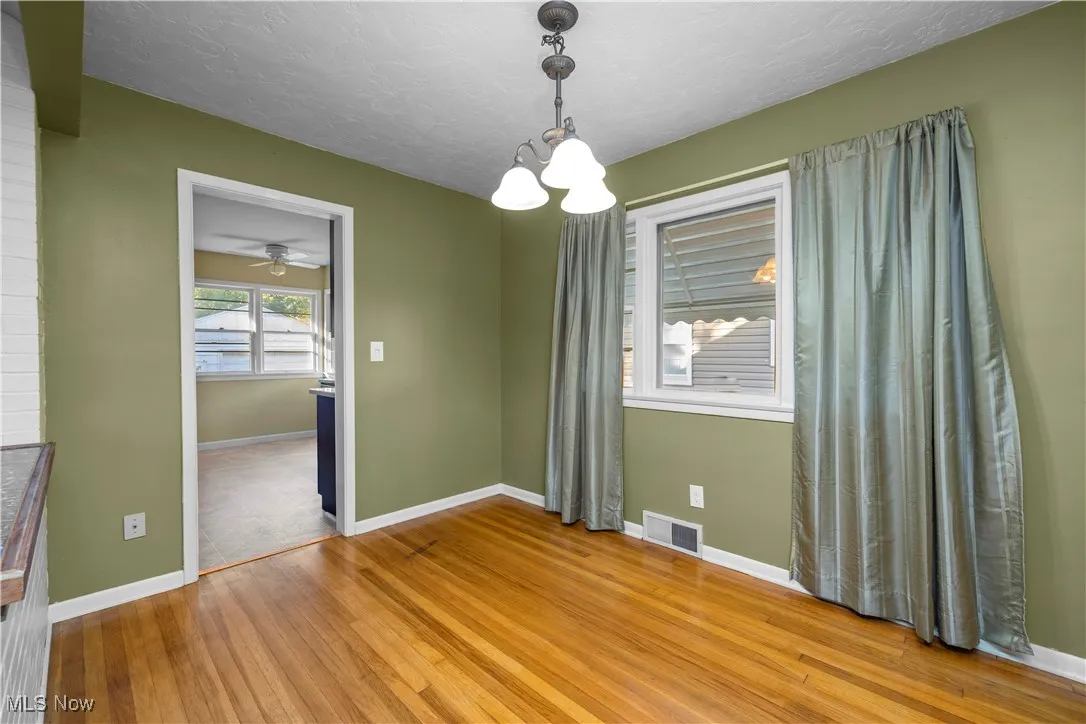 Unfurnished dining area with light wood-style floors, a chandelier, a textured ceiling, and ceiling fan