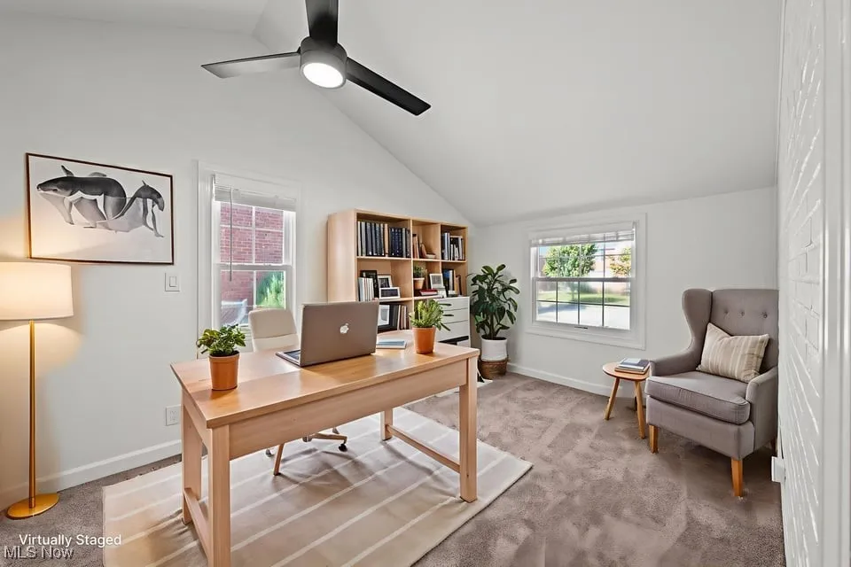 A sunny, versatile den on the main floor featuring cathedral ceilings and large windows that flood the space with natural light. Newly installed carpeting keeps things cozy underfoot, while the open layout and easy access make it a perfect home office, study, or flexible living area.