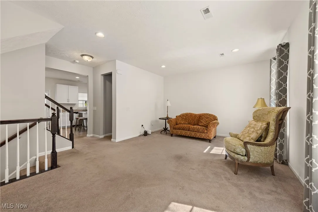 Sitting room featuring light carpet, recessed lighting, and stairway