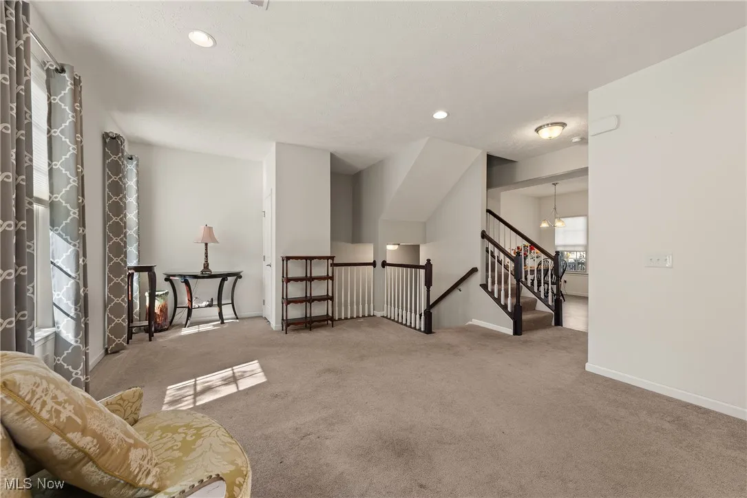 Carpeted living room with a chandelier, recessed lighting, and stairs