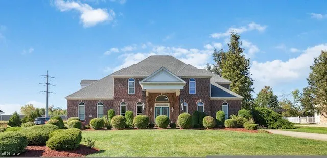 Neoclassical / greek revival house with a front lawn and brick siding