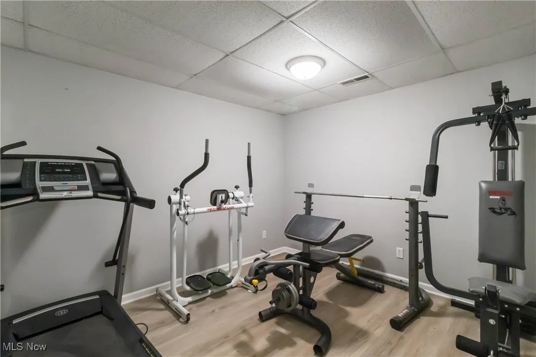 Workout area featuring a paneled ceiling and light wood-style floors