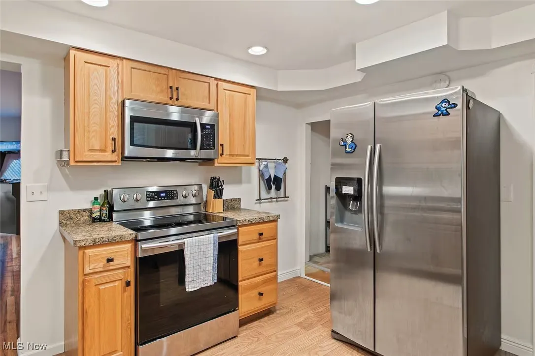 Kitchen with appliances with stainless steel finishes, light wood-style floors, recessed lighting, light countertops, and light brown cabinetry