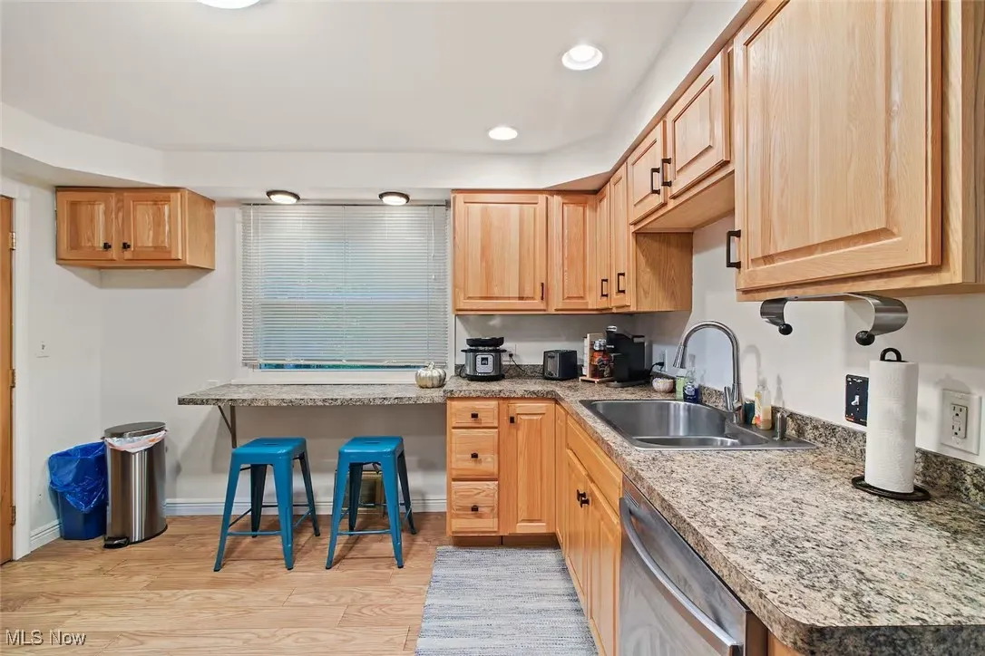 Kitchen featuring light wood-style flooring, stainless steel dishwasher, recessed lighting, light brown cabinets, and light countertops