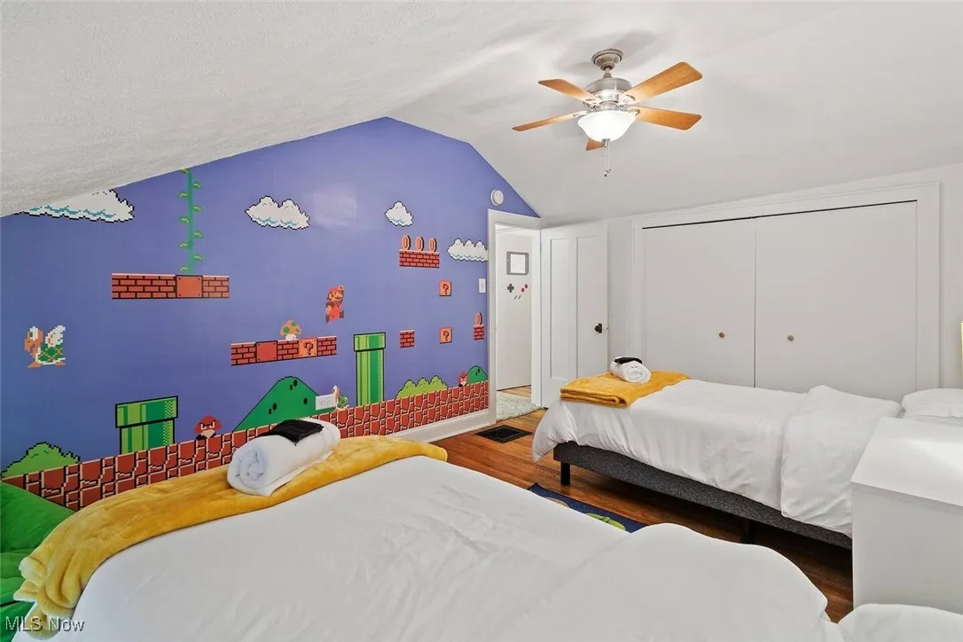 Bedroom with vaulted ceiling, wood finished floors, a closet, and ceiling fan