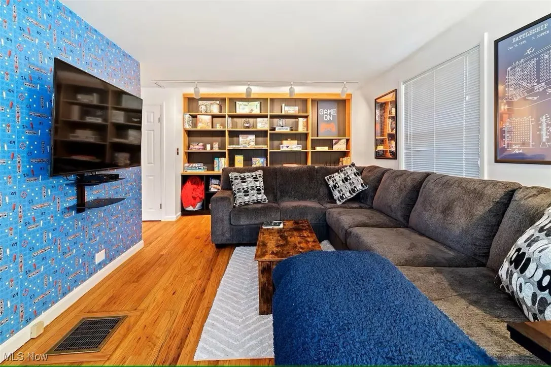 Living area with wallpapered walls, wood finished floors, and rail lighting