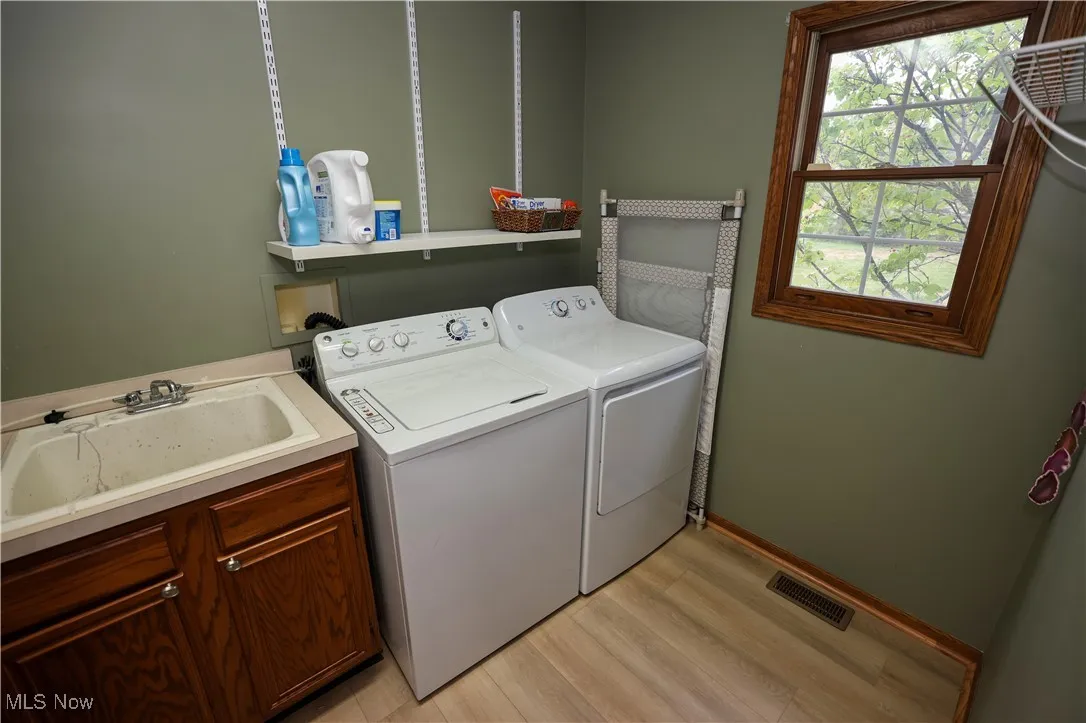 Laundry area with light wood finished floors and washing machine and clothes dryer