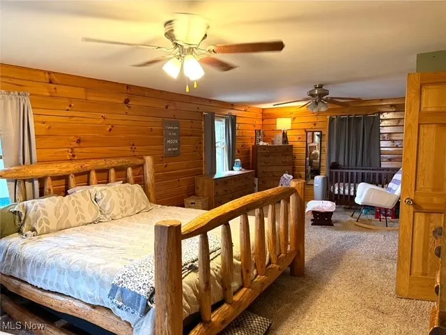 Bedroom with carpet flooring, ceiling fan, and wood walls
