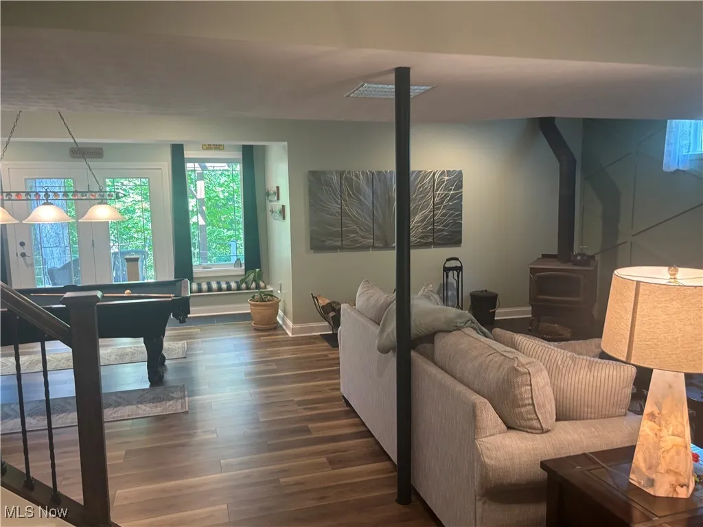 Family room with a wood stove, dark wood finished floors, and billiards table