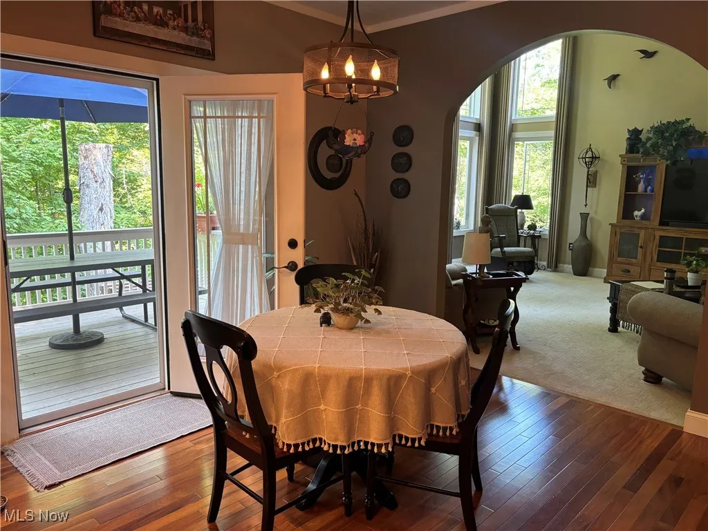 Dining space with arched walkways, hardwood / wood-style floors, a chandelier, and crown molding