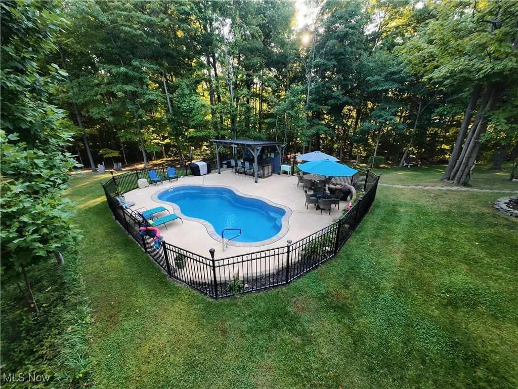 View of pool featuring a patio area, view of scattered trees