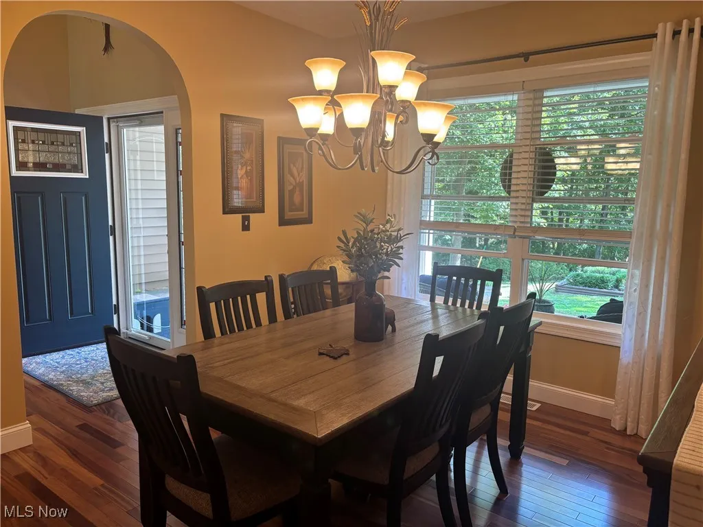 Dining room featuring a chandelier, arched walkways, and dark wood finished floors