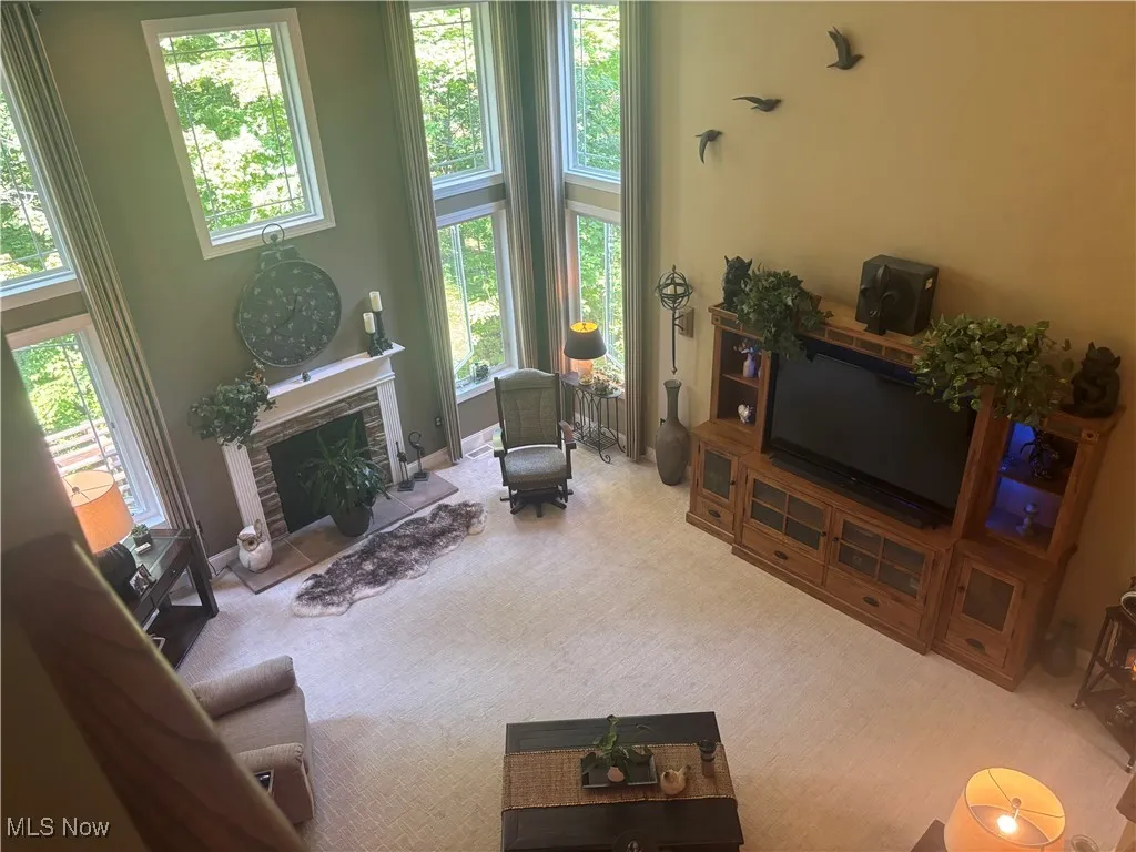 Living area featuring a towering ceiling, carpet floors, and a fireplace with raised hearth