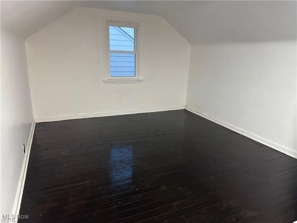 Additional living space featuring vaulted ceiling and dark wood-style floors