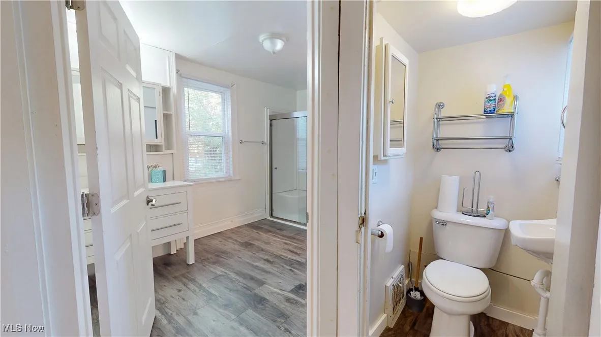 Bathroom with dark wood finished floors and a stall shower