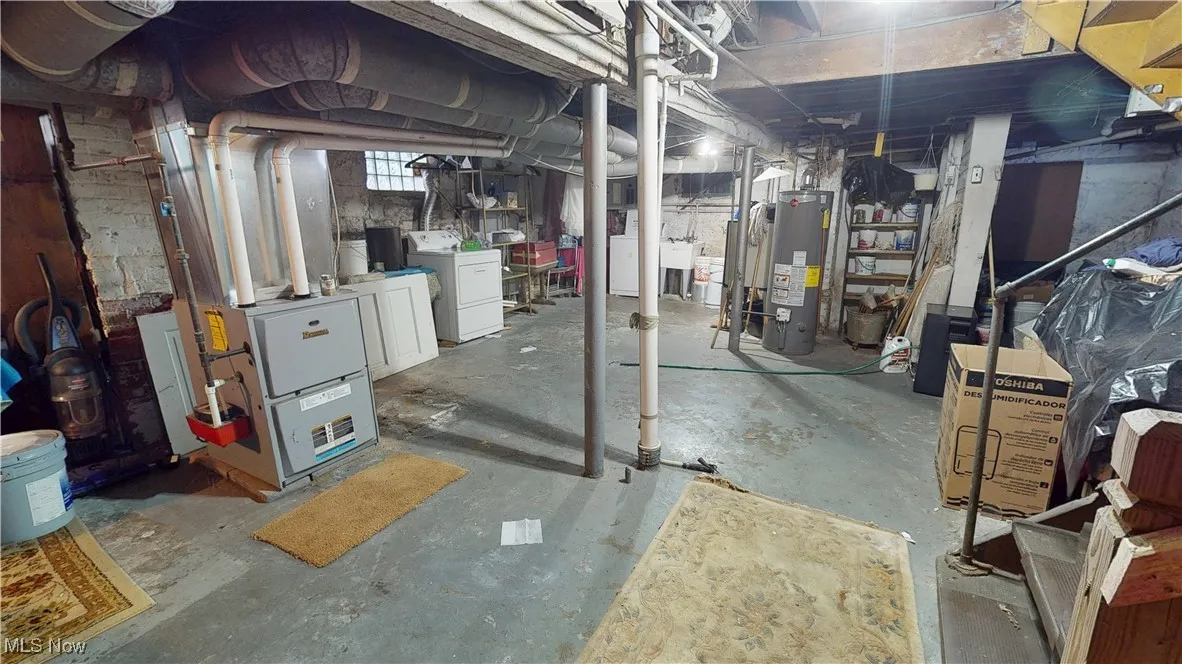 Below grade area featuring heating unit, washer / clothes dryer, and gas water heater