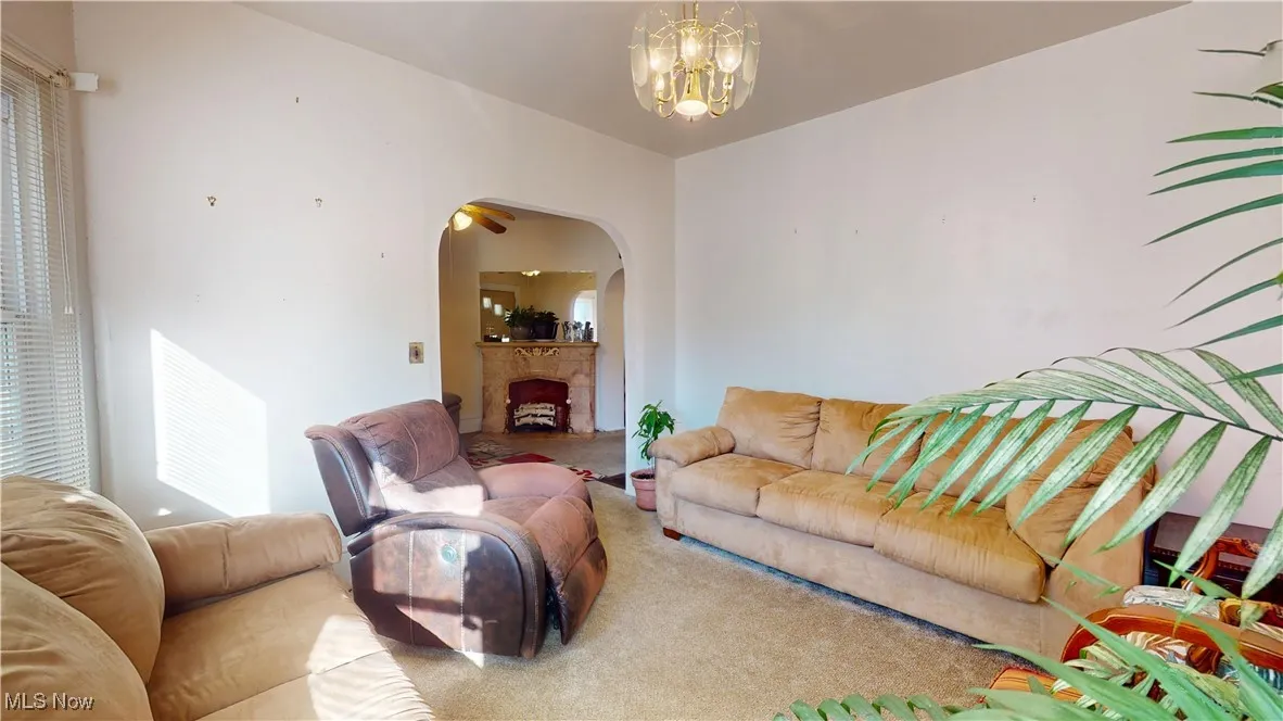 Carpeted living room featuring a fireplace, a chandelier, and arched walkways