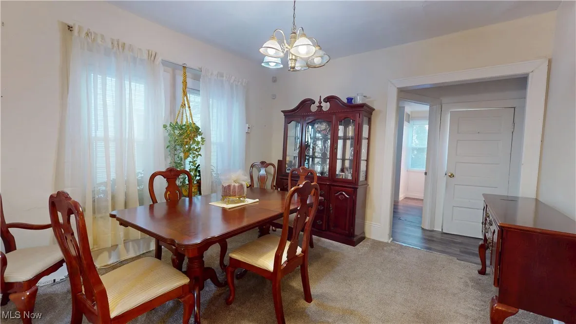 Carpeted dining room with healthy amount of natural light and a chandelier