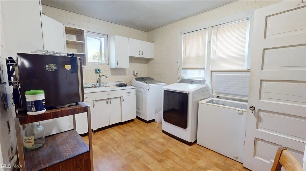 Laundry room with light wood-style flooring, independent washer and dryer, and cabinet space