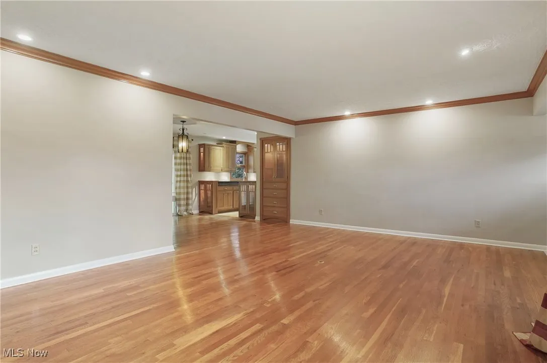 Living room with hardwood floors, ornamental molding, recessed lighting, and a stone fireplace