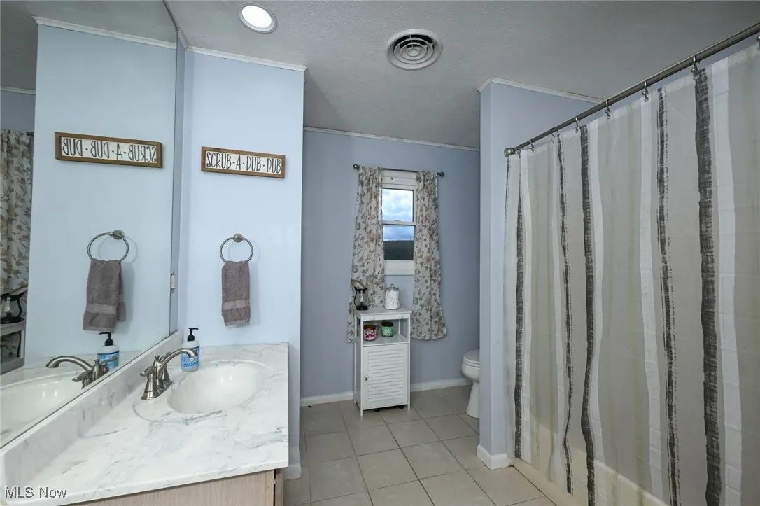Bathroom featuring vanity, light tile patterned floors, a textured ceiling, and shower / bath combination with curtain