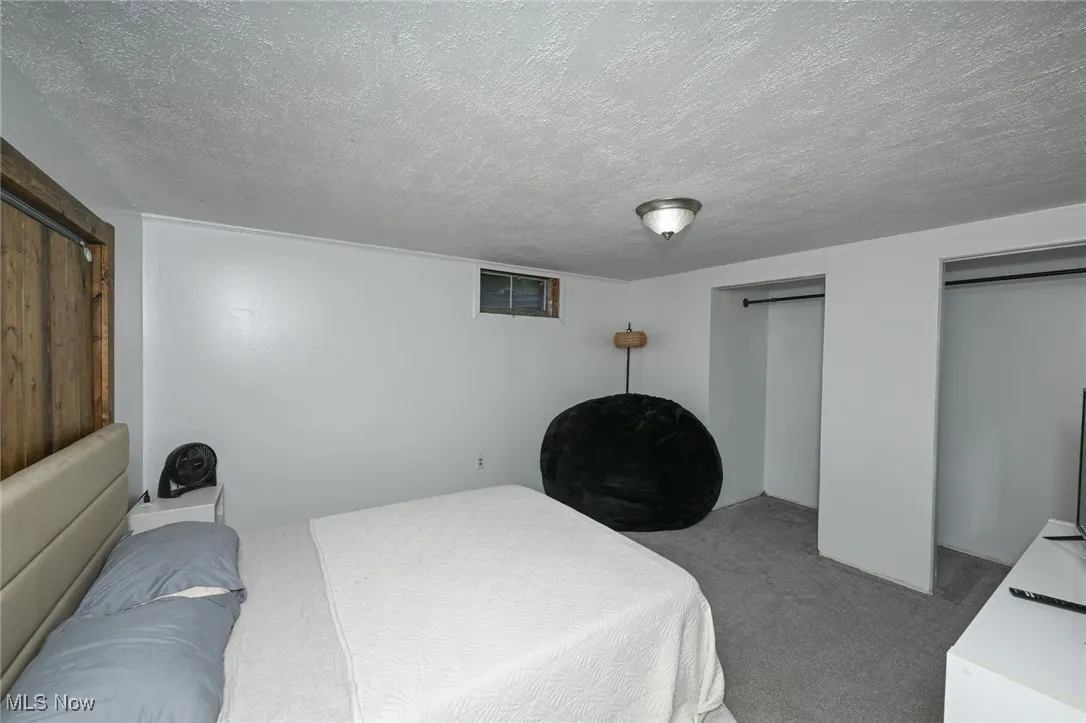 Bedroom featuring two closets, carpet floors, and a textured ceiling