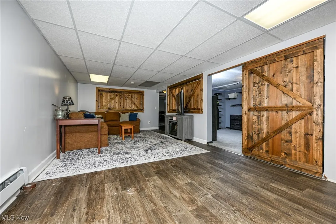 Home office with baseboard heating, a drop ceiling, and dark wood-style floors