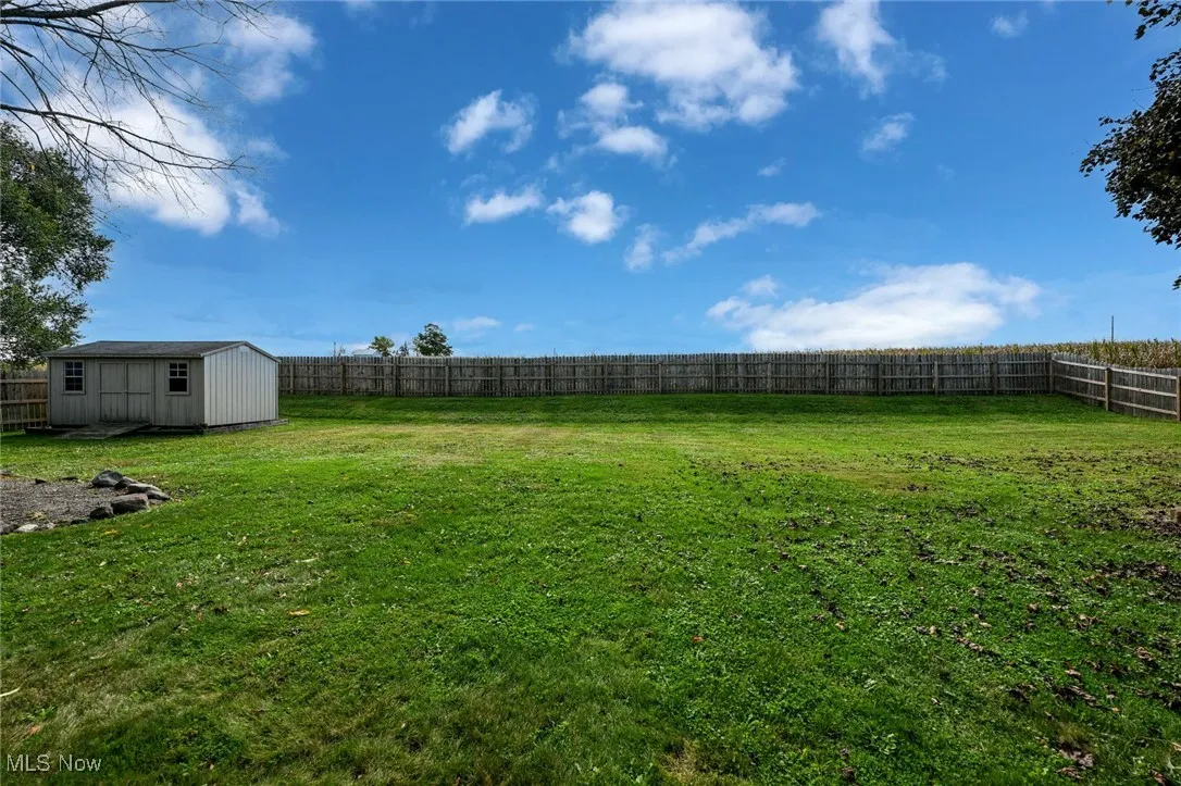 Fenced backyard featuring a storage unit