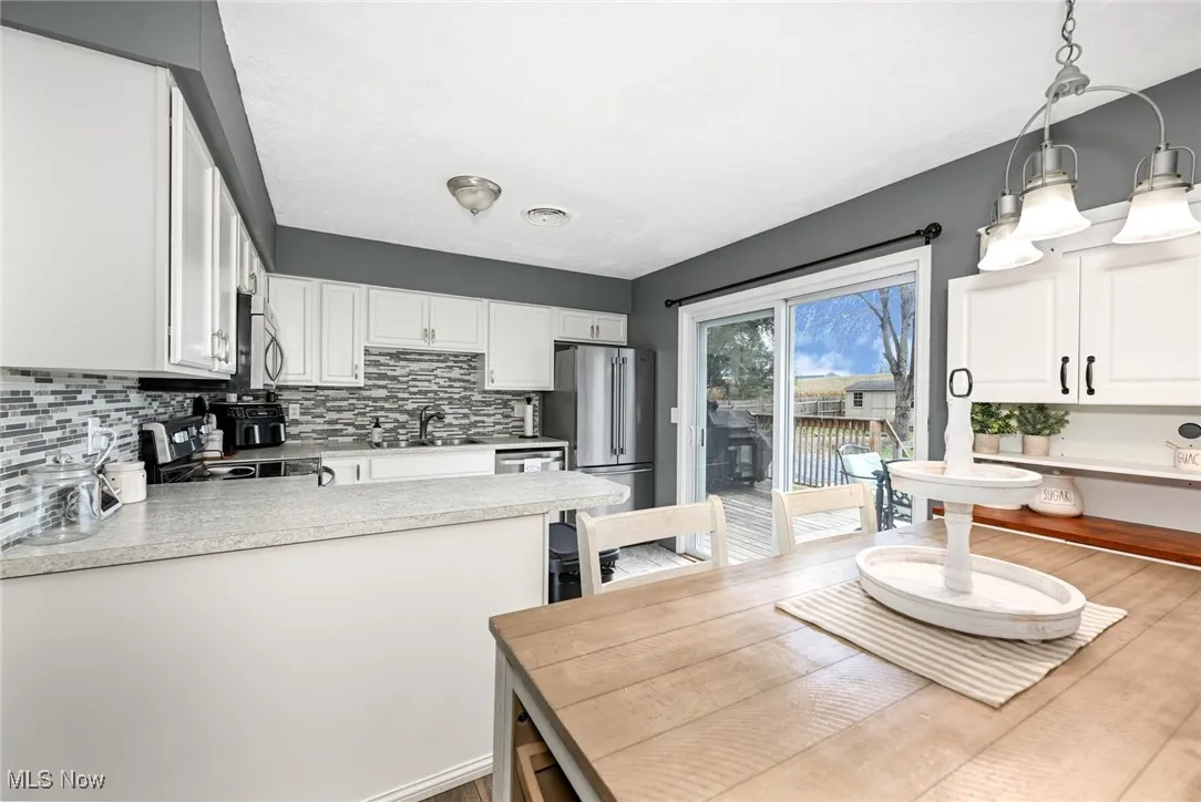 Kitchen featuring white cabinets, decorative backsplash, and light countertops