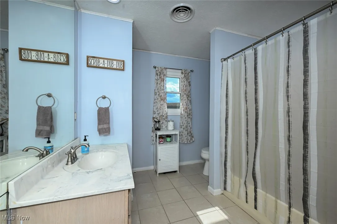 Bathroom with vanity, shower / bath combo with shower curtain, light tile patterned flooring, and a textured ceiling
