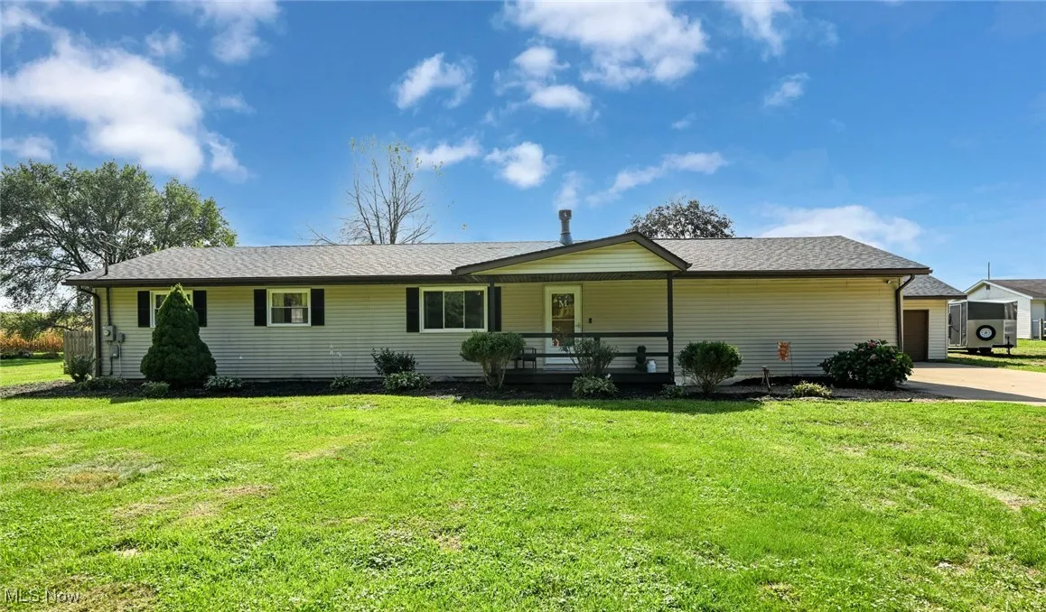Ranch-style house featuring a front lawn, roof with shingles, and concrete driveway