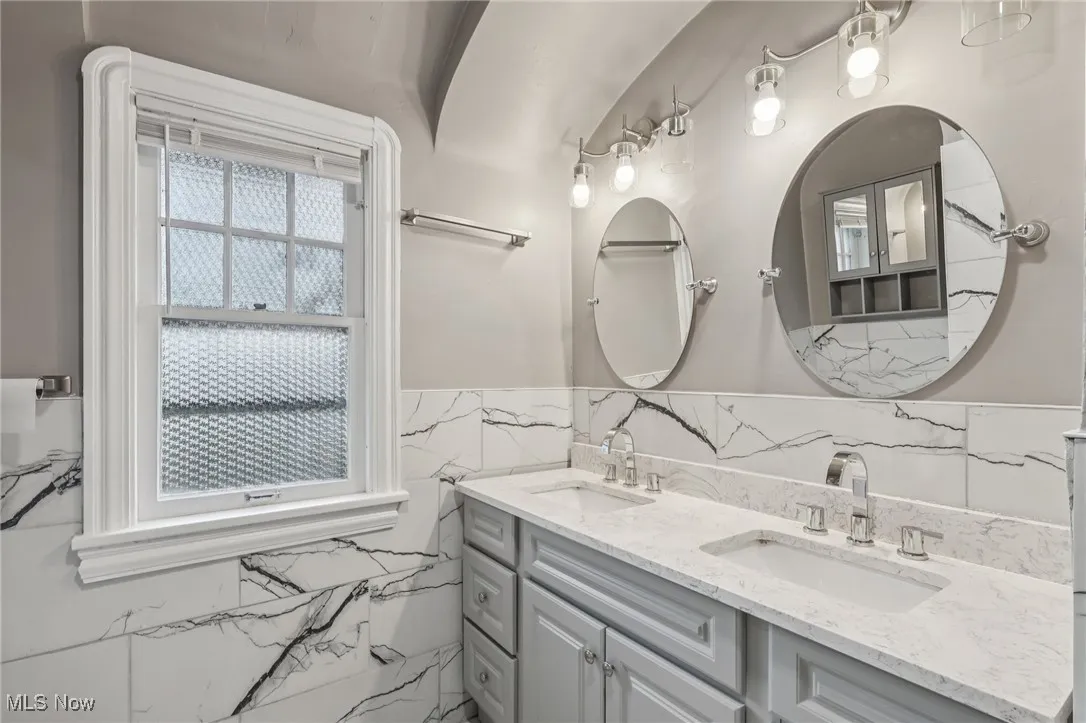 Bathroom with double vanity and tile walls