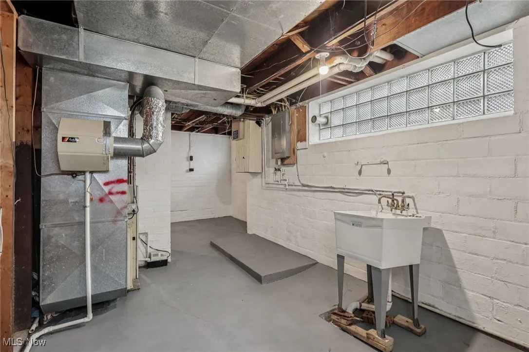 Below grade area featuring electric panel and heating unit
