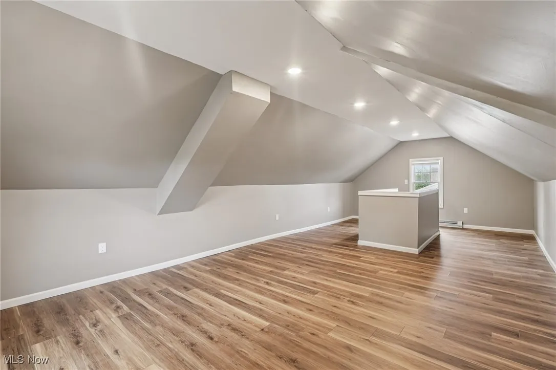 Additional living space with light wood-style flooring, lofted ceiling, recessed lighting, and a baseboard heating unit