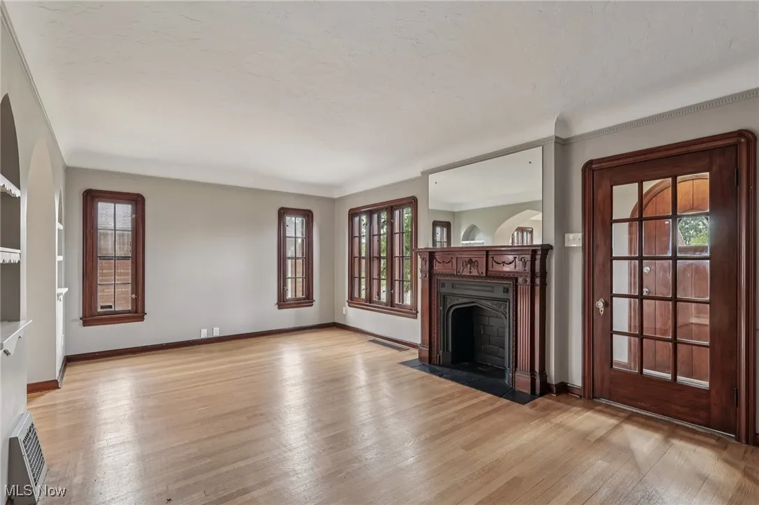 Unfurnished living room with light wood-type flooring, a fireplace with flush hearth, and crown molding