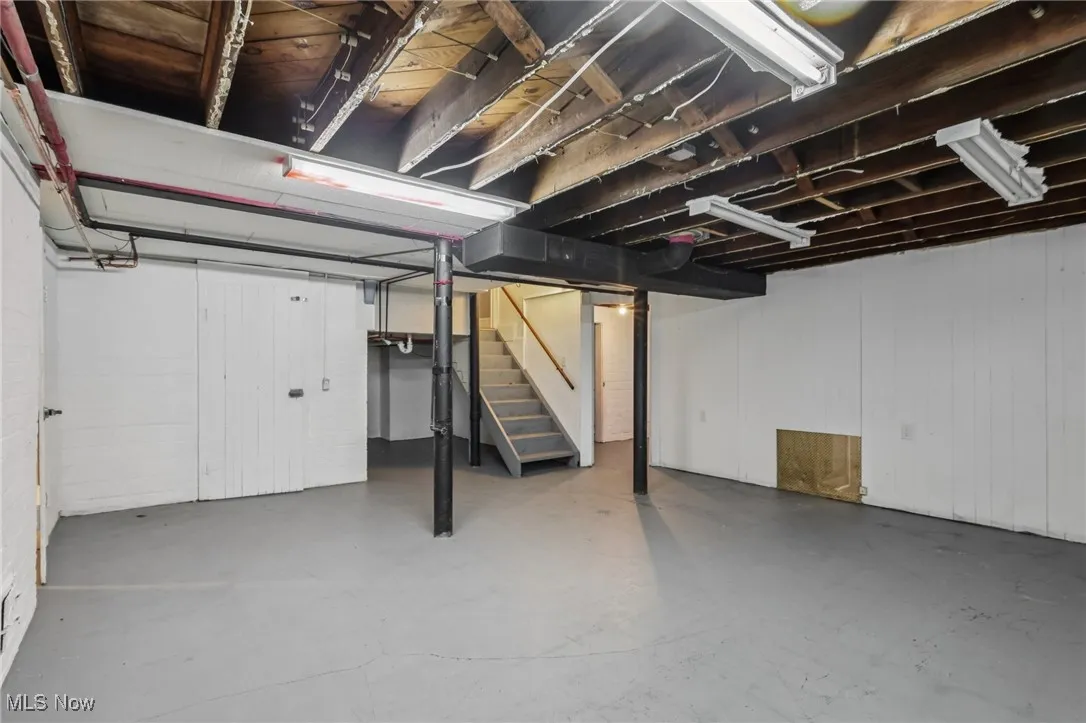 Unfinished basement featuring stairs and wood walls