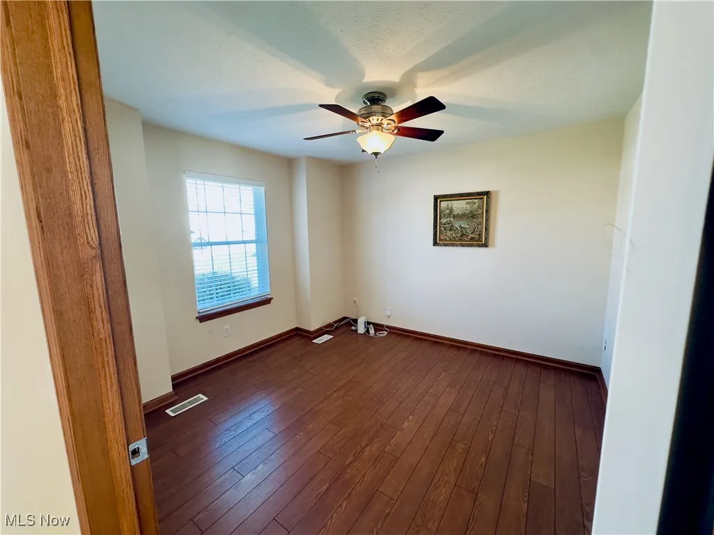 Bedroom with dark wood-style floors and a ceiling fan.