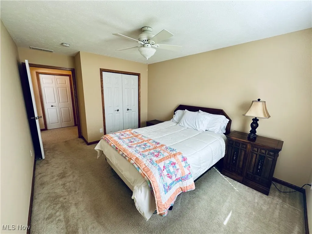 Bedroom featuring carpet floors, a ceiling fan, a closet, and a textured ceiling.