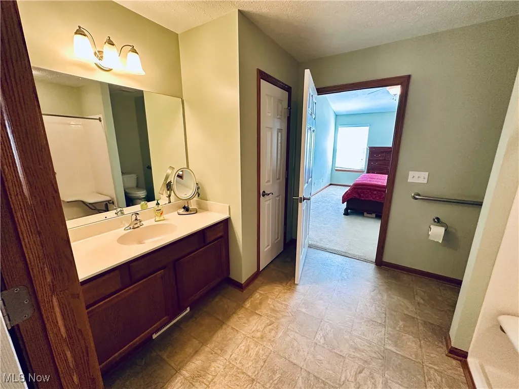 Bathroom featuring connected bathroom, vanity, and a textured ceiling.