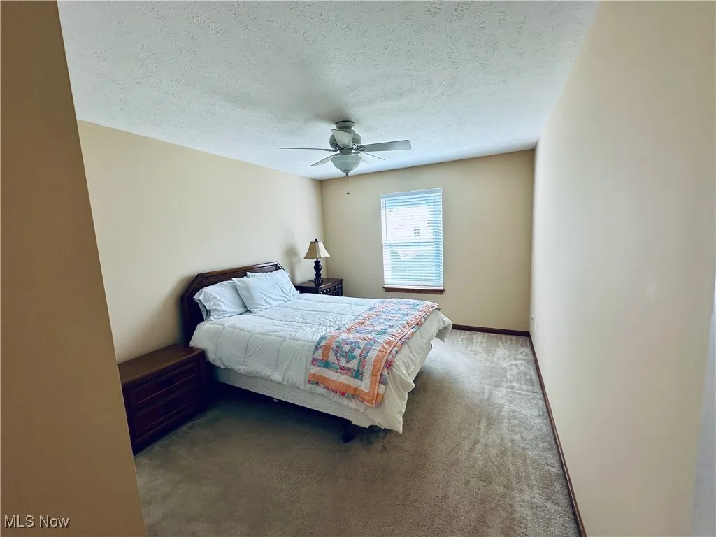 Bedroom featuring carpet flooring, a textured ceiling, and a ceiling fan.