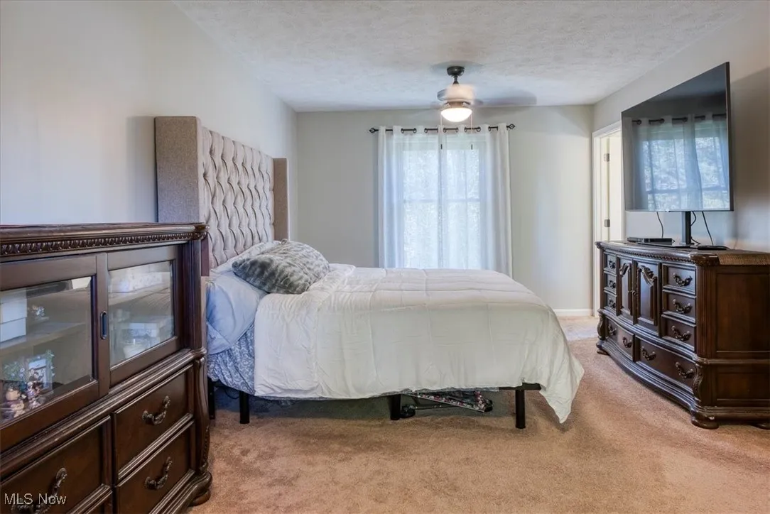 Bedroom featuring light colored carpet, a textured ceiling, and a ceiling fan