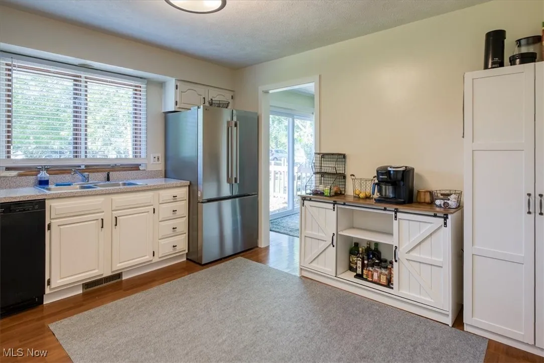 Kitchen with dark wood finished floors, freestanding refrigerator, white cabinetry, healthy amount of natural light, and a textured ceiling
