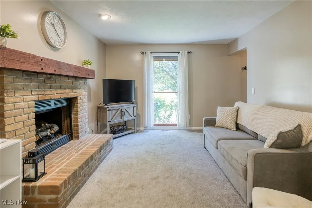 Carpeted living room featuring a brick fireplace and baseboards
