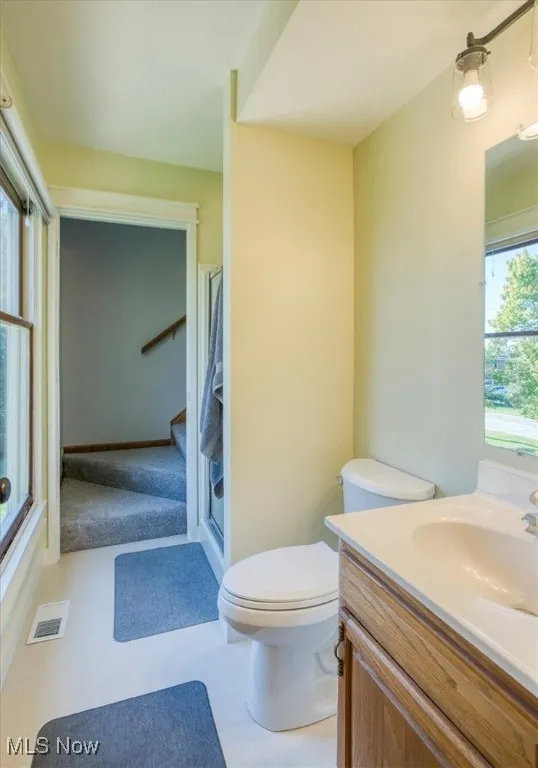 Bathroom featuring vanity, a shower with door, and light carpet