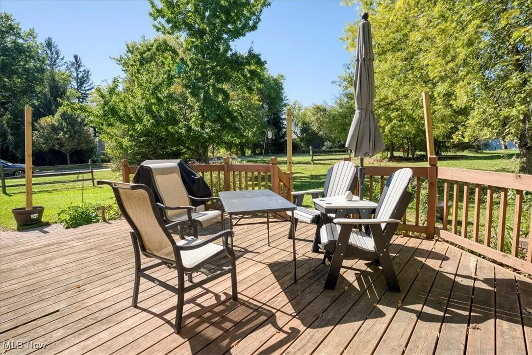 Wooden deck with a lawn and view of wooded area