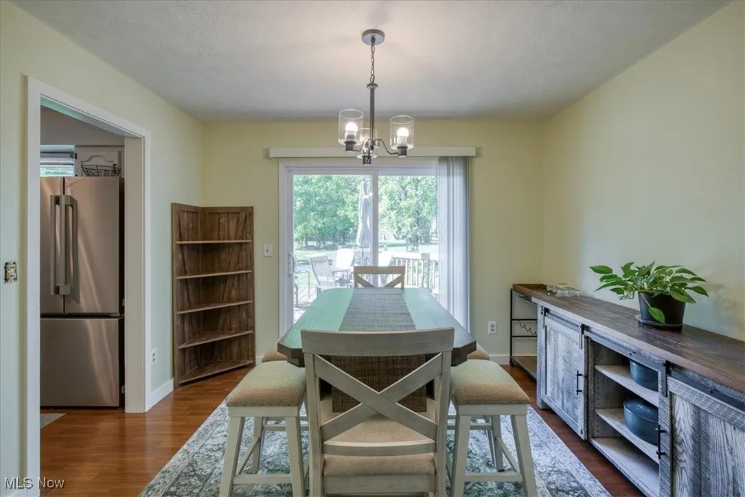 Dining space featuring dark wood-type flooring, a chandelier, and a textured ceiling