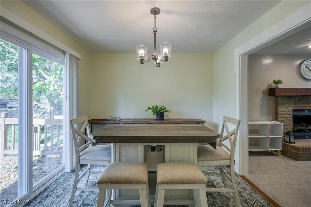 Dining space with a brick fireplace, carpet flooring, and a chandelier