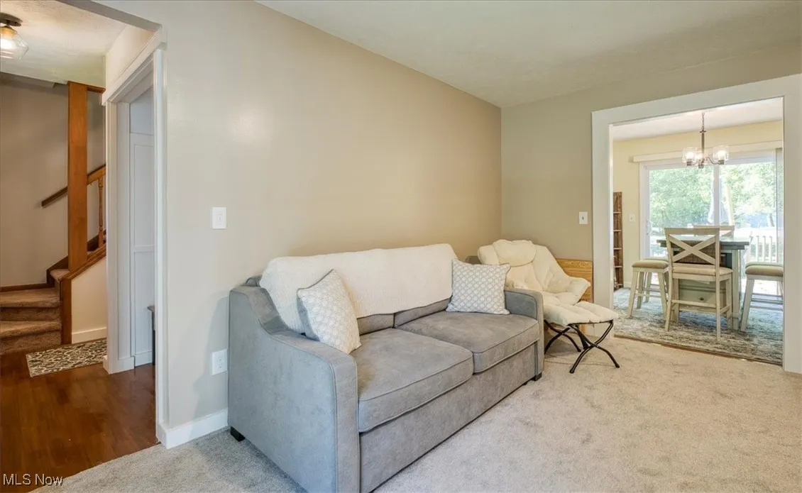 Carpeted living area with stairway and a chandelier