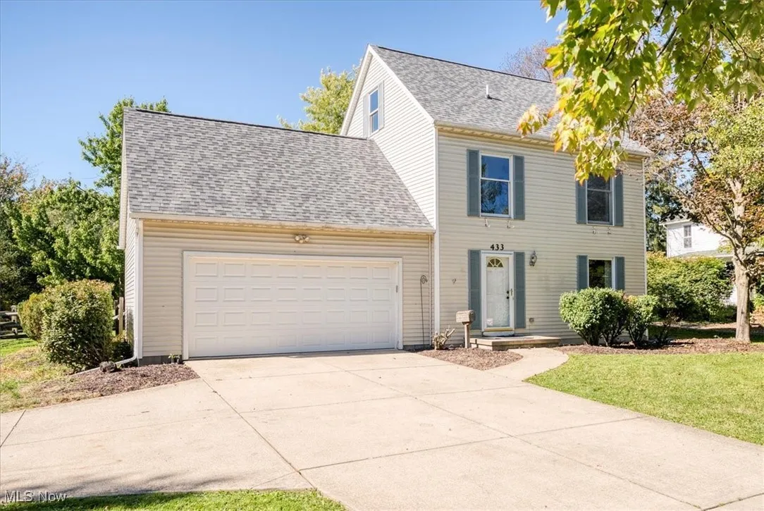 Colonial-style house with roof with shingles, a garage, driveway, and a front yard